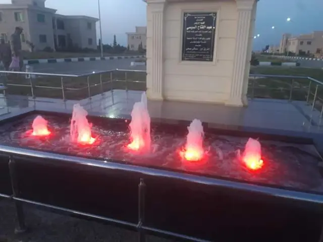 Fountain in front of a foundation plaque, red scene