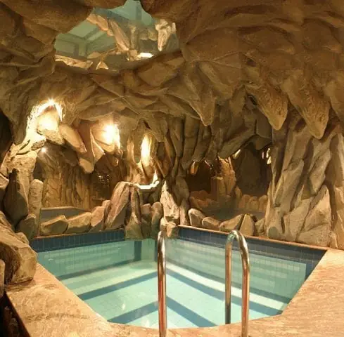 Grotto-style spa pool with warm rock lighting and stainless ladder