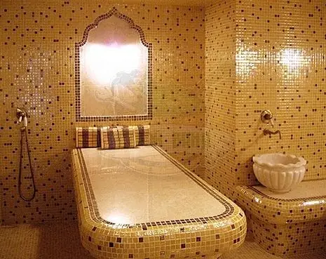 Hammam in golden mosaic with massage slab and basin