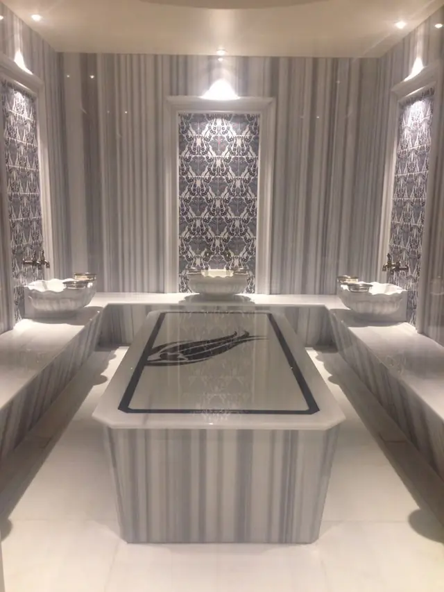 Hammam with marble massage platform and striped walls